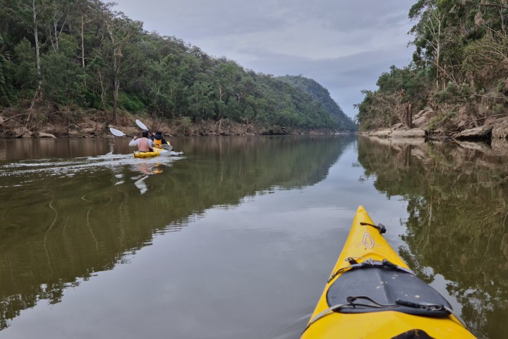a boat floating along a river next to a body of water